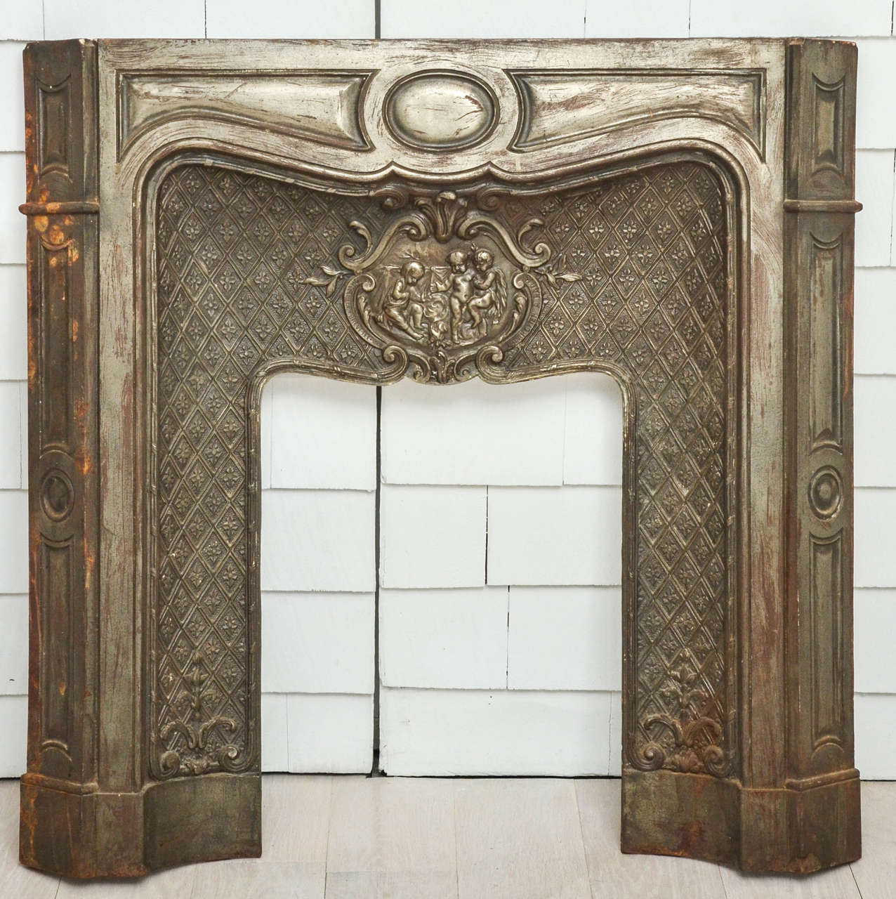 19th century French cast iron fireplace. Featuring a C-scroll cartouche enclosing putti.